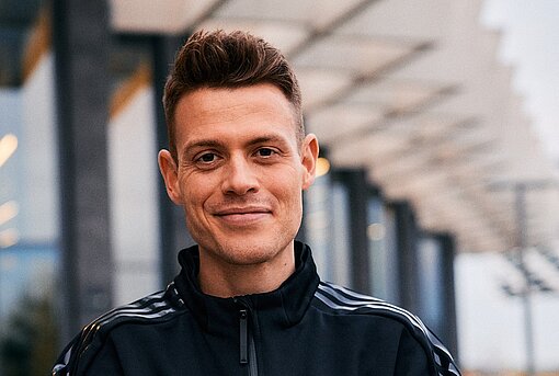 Philipp Pflieger Ein junger Mann im Trainingsanzug vor einer Sporthalle
