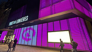 Das Hotel Port des Lumières ist im Dunkeln anlässlich des Weltmädchentages pink beleuchtet.