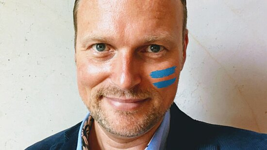 Kai Gehring mit dem blauen Girls Get Equal Gleichzeichen auf der Wange.