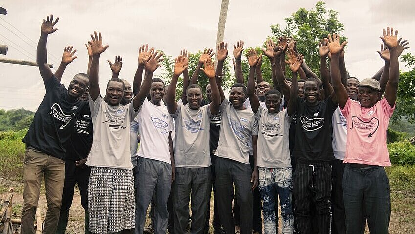 Die engagierten Männer des Väterclubs in Ghana Eine Gruppe Männer reckt begeistert die Arme in die Luft und posiert für ein Gruppenbild