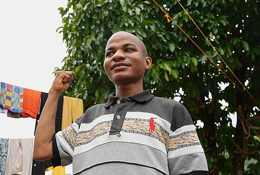 Ein junger Mann hält eine Faust als Symbol für Stärke hoch