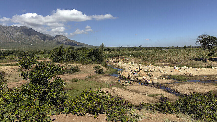Landschaft im Bezirk Phalombe, südöstliches Malawi Trockene Landschaft mit vereinzelten Bäumen, Büschen und Gräsern und einem begrünten Hügel im Hintergrund