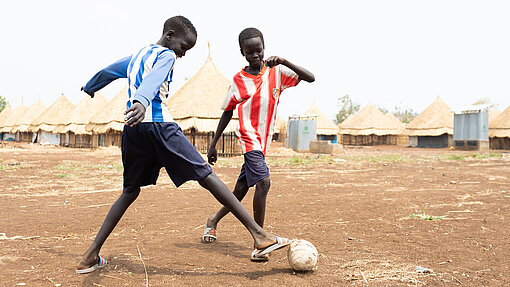 Lim und Akim spielen mit einem Fußball.