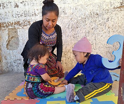 Eine Frau spielt mit zwei Kleinkindern