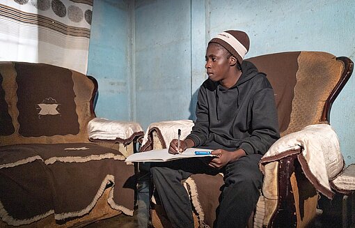 Eine junge Frau sitzt in einem Sessel aus mit braunem Velours-Bezug