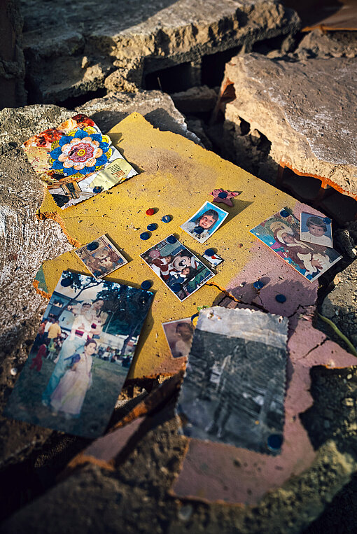 Reste von Fotos in Trümmerteilen eines Gebäudes