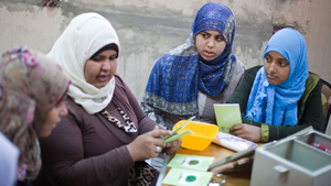 Vier Frauen in Hijabs sitzen an einem Tisch und organisieren ihre Spargruppe