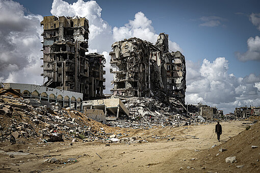 Zerstörte Gebäude und Trümmerlandschaft nach Kriegsschäden in Gaza mit einer Person im Vordergrund