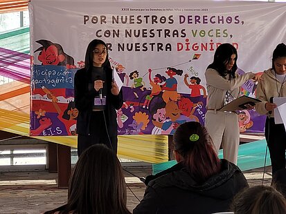 Mehrere junge Frauen sprechen auf einer Bühne in Mikrofone