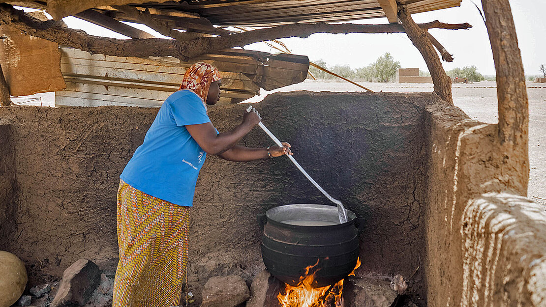 Ein Frau rührt im Kochtopf