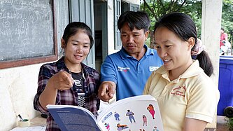 Khat und Phasouk betrachten gemeinsam Trainingsunterlagen von Plan International