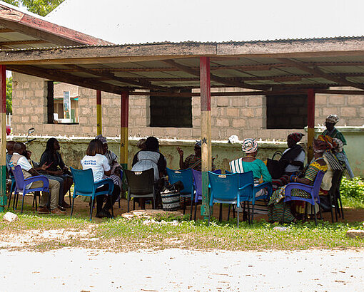 Die Königinnenmütter sitzen draußen unter einem Dach in ihrer Gemeinde