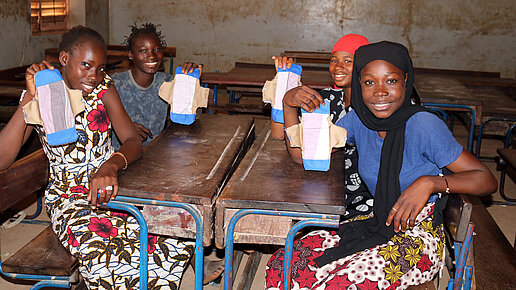Junge Frauen zeigen ihre wiederverwendbaren Binden, die sie in einem Workshop hergestellt haben. 