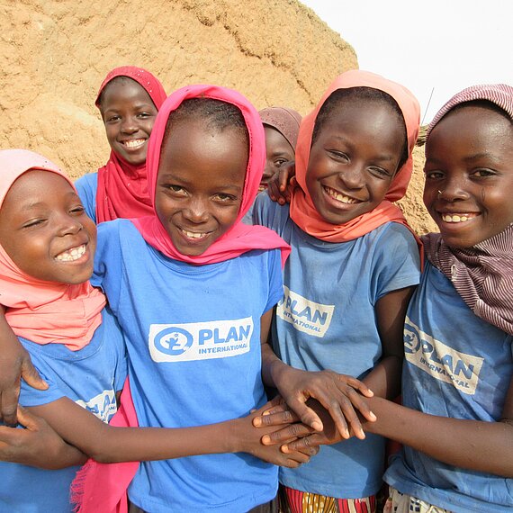 Mädchen mit Plan-Shirts umarmen sich und lachen