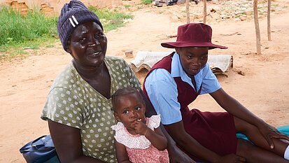 Eine Frau, ein Mädchen und ein Kind sitzen auf dem Boden