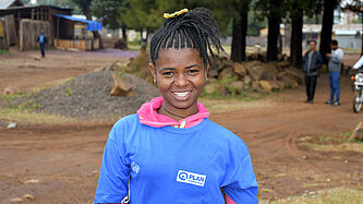 Eine junge Frau schaut lächelnd in die Kamera.