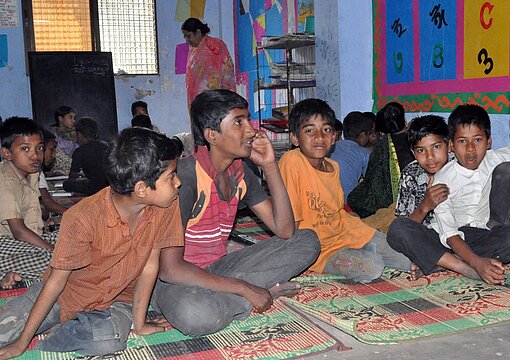 Kinder sitzen auf dem Fußboden eines Drop in Centre