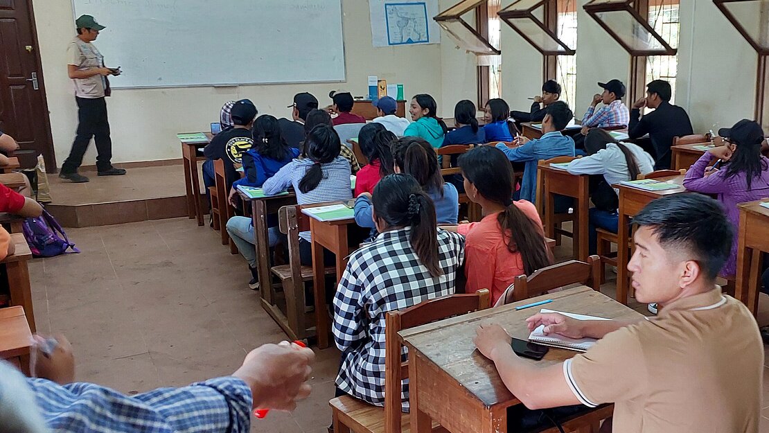 Jugendliche sitzen in einem Klassenzimmer und lauschen dem Lehrer.