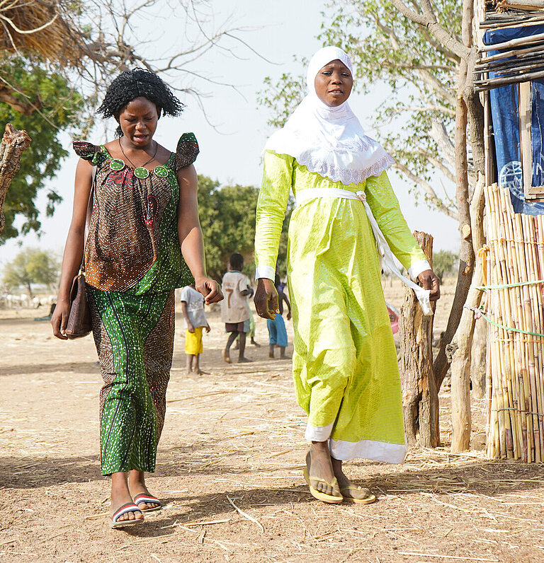 Zwei Frauen laufen durch ein Dorf