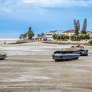 Boote liegen an einem Strand, über dem dunkle Wolken herantreiben