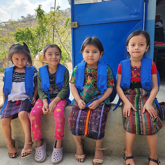 Vier Mädchen sitzen auf einer Mauer
