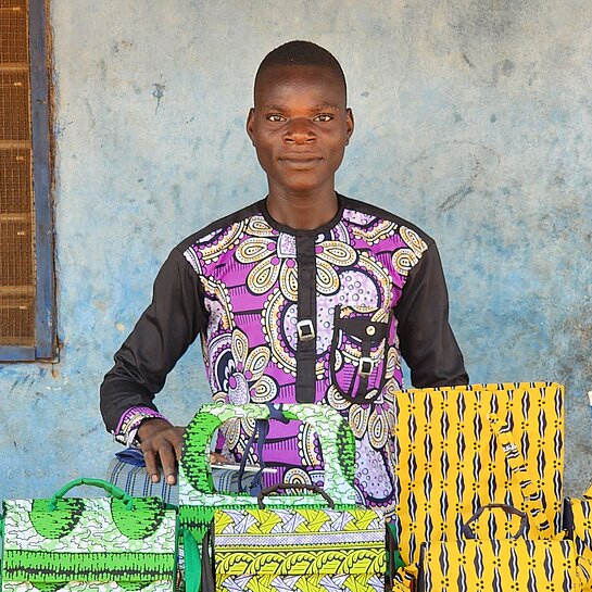 Junger Mann steht vor einem Tisch mit selbstgemachten Gegenständen