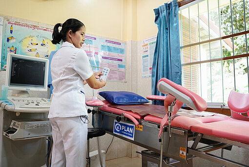 Eine Hebamme richtet ein neues Untersuchungsbett in einem Gesundheitszentrum für die nächste Patientin her.