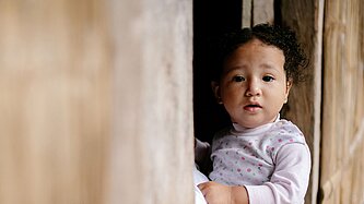 Mayras kleine Tochter blickt aus einem Fenster ihres Zuhauses in der ecuadorianischen Provinz Manabí.