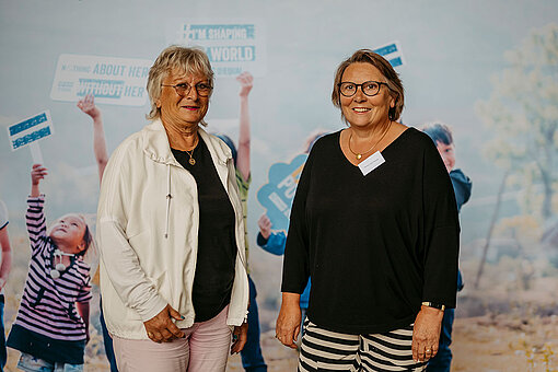 Dr. Heike Solbrig-Lebuhn und Hanne Lloyd-Heume beim Stiftungstreffen 2024. Dr. Heike Solbrig-Lebuhn und Hanne Lloyd-Heume beim Stiftungstreffen 2024 vor einem Hintergrund mit Kindern und Empowerment-Slogans.