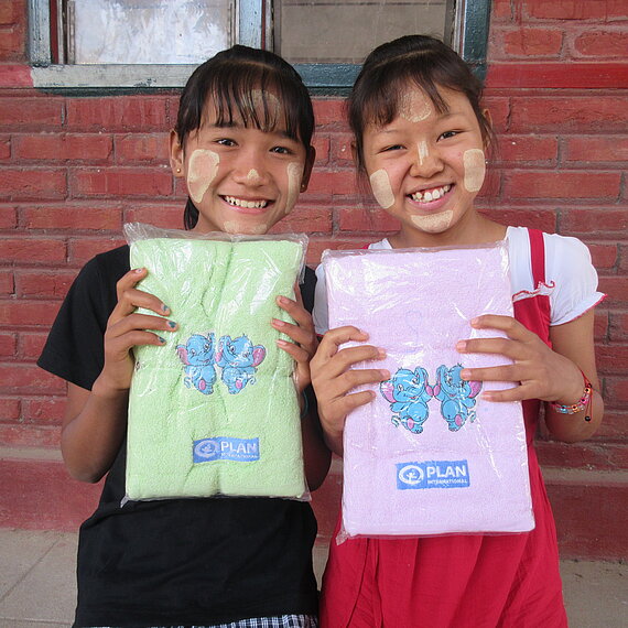 Zwei Mädchen halten bedruckte Handtücher von Plan in den Händen