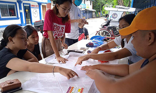 Gruppe Jugendlicher arbeitet über eine Straßenkarte gebeugt zusammen