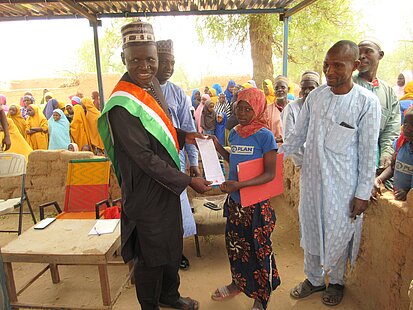 Ein Mädchen empfängt ein Dokument von einem Würdenträger