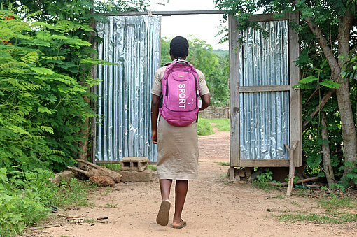 Ein Mädchen im Norden von Benin auf dem Weg zur Schule Ein Mädchen läuft durch ein Tor