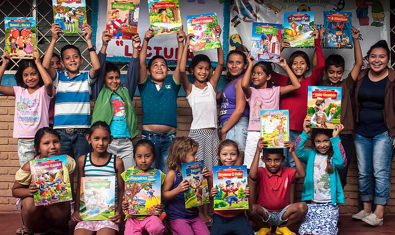 Kindergruppe halten bunte Bücher hoch.