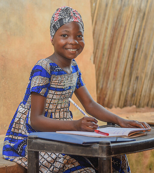 Anne sitzt an einem Tisch und schreibt