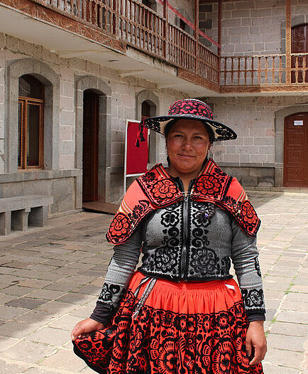 Jessica aus Peru steht auf einem Dorfplatz in traditioneller Kleidung