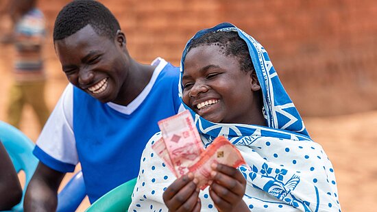 Bild: Eine Frau hält glücklich Geld-Scheine in der Hand