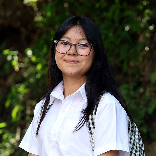 Adriana steht draußen in ihrer Gemeinde in El Salvador