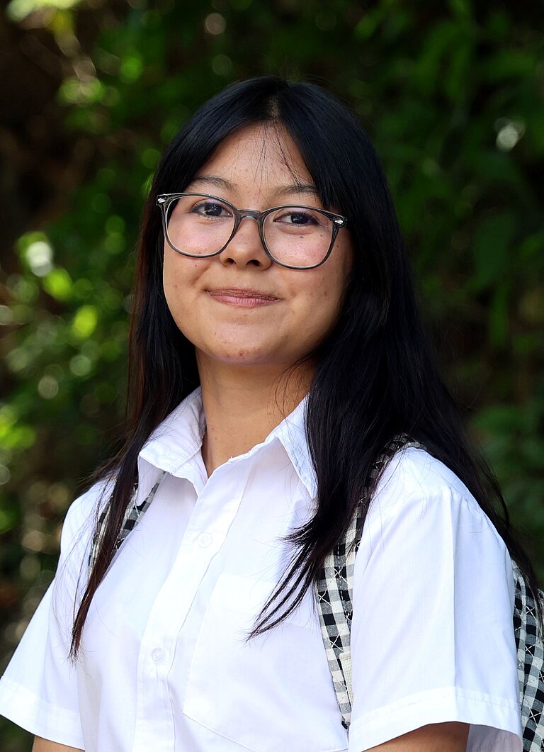 Adriana steht draußen in ihrer Gemeinde in El Salvador