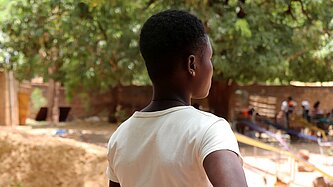 Aline steht draußen in ihrer Gemeinde in Burkina Faso 