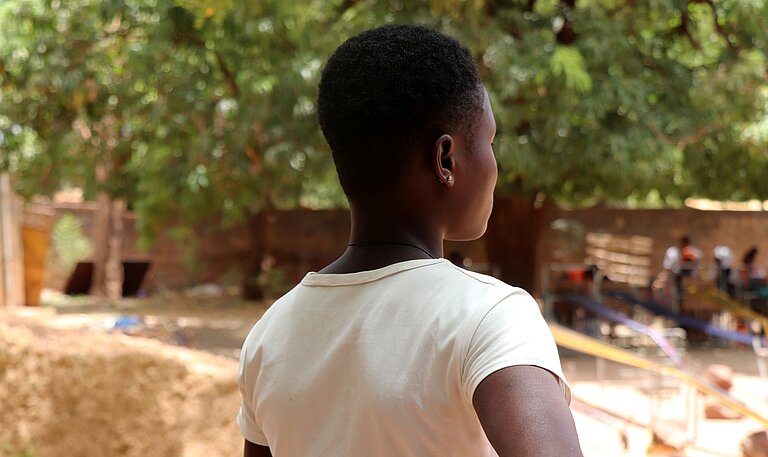 Aline steht draußen in ihrer Gemeinde in Burkina Faso 