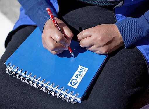 Ein Notizblock mit dem Logo der Kinderrechtsorganisation Plan International