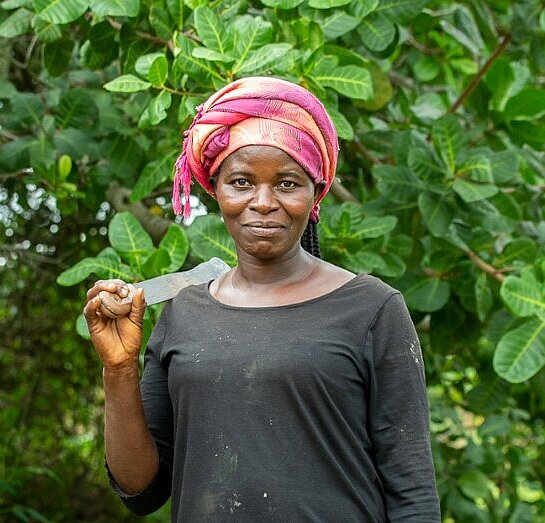 Frau vor Cashewfarm stehend