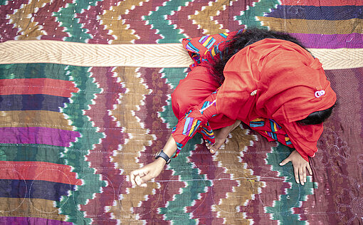 Eine junge Frau sitzt auf einer Decke
