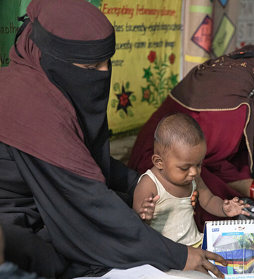 Frauen im Niqab lesend, ein Kind auf dem Schoß