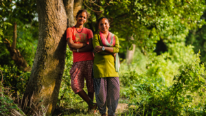 Zwei Frauen aus Nepal stehen nebeneinander an einem Baum und zeigen Stärke und Zusammenhalt im Kontext von Gleichberechtigung