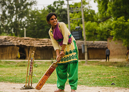 Cricket spielendes Mädchen in Indien Ein Mädchen in Indien spielt Cricket
