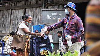 Plan-Mitarbeitende verteilen Hygienekits an Bewohner*innen der Projektgemeinden. ©Plan International