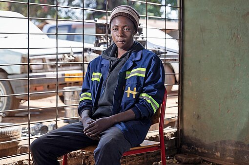 Eine Frau sitzt auf einem Stuhl im Büro einer kleinen Kfz-Werkstatt