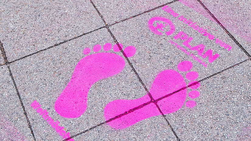 Mit pinker Farbe auf den Boden gesprühte Fußspuren